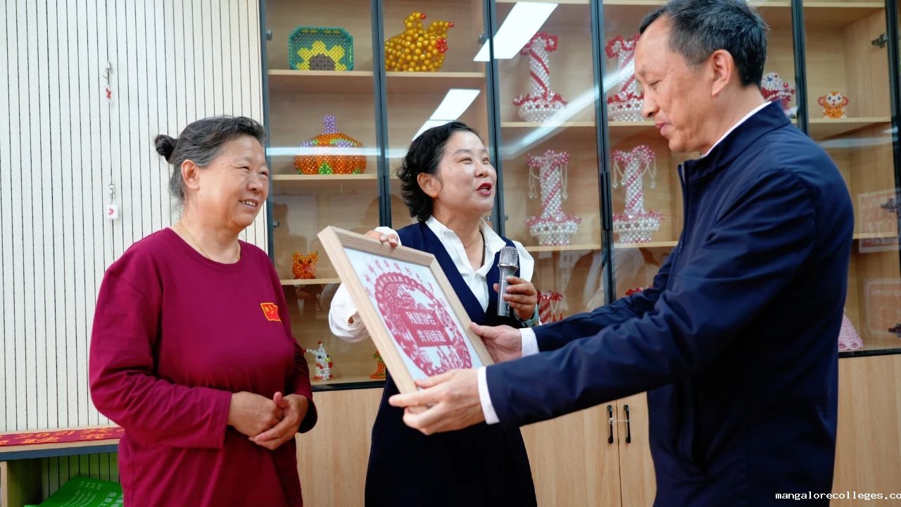 图为中国残联党组成员、副主席张卫星在武汉市武昌区华锦社区听工作人员介绍残疾人剪纸作品